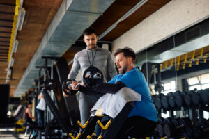 Man lifting weights under the guidance of a personal trainer in a gym