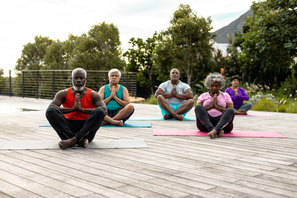 Group of seniors practicing outdoor yoga meditation on mats.