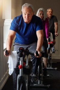 Older man leading a group of senior adults in a spin class